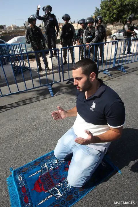 Israeli police stand guard as Palestinian Muslims pray on the streets of the Wadi al-Joz neighbourhood in east Jerusalem during the Friday prayers following restrictions by Israeli police preventing Palestinians under 40...