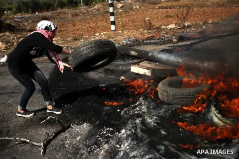 A female Palestinian protester burns tires during clashes with Israeli security forces near the Beit El settlement on the outskirts of Ramallah in the West Bank, on October 16, 2015. The unrest that has engulfed Jerusale...