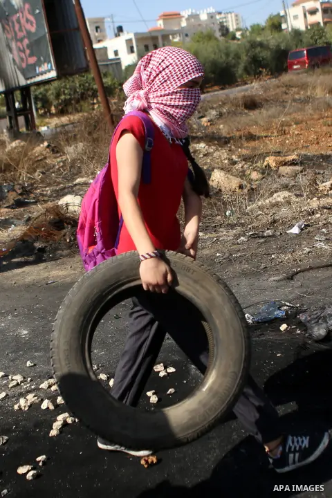 A female Palestinian protester burns tires during clashes with Israeli security forces near the Beit El settlement on the outskirts of Ramallah in the West Bank, on October 16, 2015. The unrest that has engulfed Jerusale...