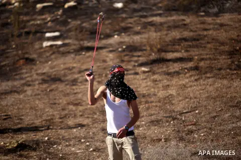 A Palestinian protester hurls stones towards Israeli security forces during clashes near the Beit El settlement on the outskirts of Ramallah in the West Bank, on October 16, 2015. The unrest that has engulfed Jerusalem a...