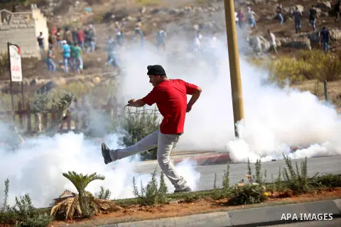 A Palestinian kicks back a tear gas canister towards Israeli security forces during clashes near the Beit El settlement on the outskirts of Ramallah in the West Bank, on October 16, 2015. The unrest that has engulfed Jer...