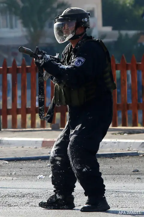 A member of Israeli security forces fires tear gas towards Palestinian protesters during clashes near the Beit El settlement on the outskirts of Ramallah in the West Bank, on October 16, 2015. The unrest that has engulfe...