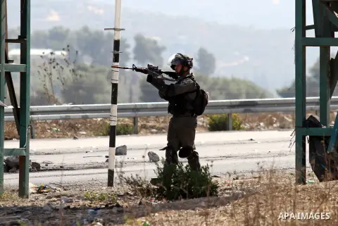 A member of Israeli security forces aims at Palestinian protesters during clashes at the Israeli Hawara checkpoint near the West Bank city of Nablus October 16, 2015. The unrest that has engulfed Jerusalem and the occupi...