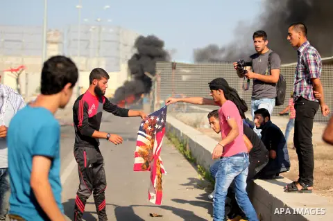 A Palestinian protester burns U.S flag during clashes with Israeli security forces at the Erez crossing checkpoint in the northern Gaza Strip October 16, 2015. The unrest that has engulfed Jerusalem and the occupied West...