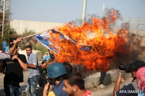A Palestinian protester burns Israeli flag during clashes with Israeli security forces at the Erez crossing checkpoint in the northern Gaza Strip October 16, 2015. The unrest that has engulfed Jerusalem and the occupied...