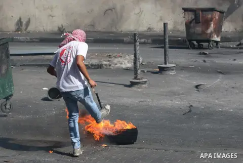 A Palestinian protester kicks a burning tire towards Israeli security forces during clashes at the main entrance of the West Bank city of Bethlehem on October 16, 2015. The unrest that has engulfed Jerusalem and the occu...