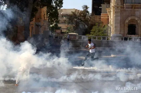 A Palestinian protester runs for cover from tear gas during clashes with Israeli security forces at the main entrance of the West Bank city of Bethlehem on October 16, 2015. The unrest that has engulfed Jerusalem and the...