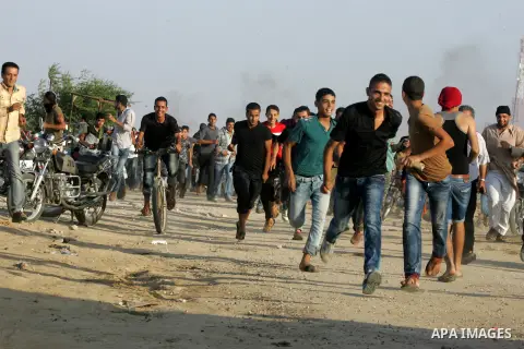 Palestinian protesters run for cover from tear gas during clashes with Israeli security forces near the border fence between Israel and the southern Gaza Strip October 16, 2015. The unrest that has engulfed Jerusalem and...