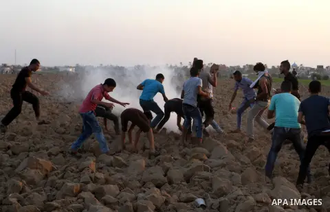 Palestinian protesters run for cover from tear gas during clashes with Israeli security forces near the border fence between Israel and the southern Gaza Strip October 16, 2015. The unrest that has engulfed Jerusalem and...