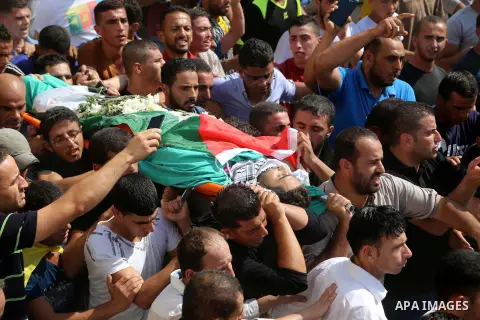Relatives carry the body of Palestinian Eyad Awawda, who while disguised as a news photographer, stabbed and wounded a soldier at an entrance to the West Bank settlement of Kiryat Arba before being shot dead, during his...