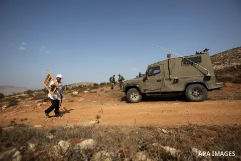 A Palestinian farmer walks past Israeli soldiers as he works at his farm during the olive harvest season in the West Bank city of Nablus on Oct. 19, 2015. Photo by Nedal Eshtayah