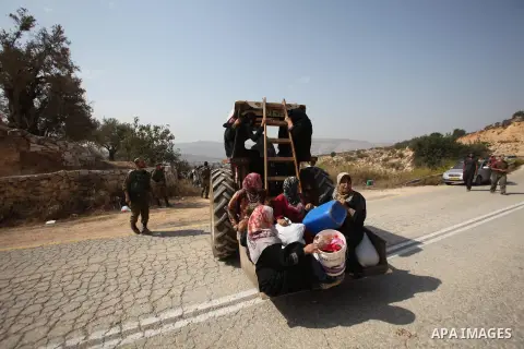 Palestinian farmers ride a tractor past Israeli sodliers during the olive harvest season in the West Bank city of Nablus on Oct. 19, 2015. Photo by Nedal Eshtayah