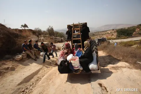 Palestinian farmers ride a tractor past Israeli settlers during the olive harvest season in the West Bank city of Nablus on Oct. 19, 2015. Photo by Nedal Eshtayah