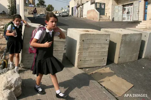 Palestinian school girls walk between cement blocks at a newly erected checkpoint in Jerusalem's neighborhood of Jabal al-Mokaber on October 19, 2015. Israeli police began erecting a wall in east Jerusalem to protect a J...