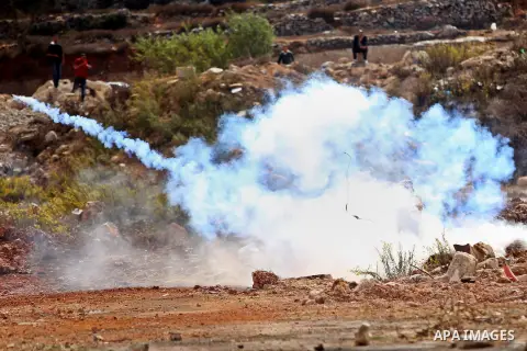 A Palestinian protester uses a sling shot to throw back a tear gas canister during clashes with Israeli security forces near the Jewish settlement of Beit El, near the West Bank city of Ramallah October 20, 2015. Trigger...