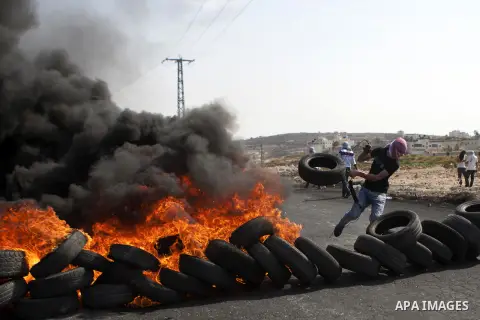A Palestinian protester burns tires during clashes with Israeli security forces near the Jewish settlement of Beit El, near the West Bank city of Ramallah October 20, 2015. Triggered by Israeli incursions into the Al-Aqs...