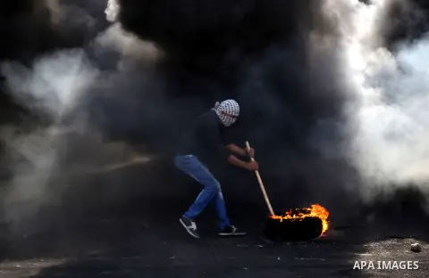 A Palestinian protester burns tires during clashes with Israeli security forces near the Jewish settlement of Beit El, near the West Bank city of Ramallah October 20, 2015. Triggered by Israeli incursions into the Al-Aqs...