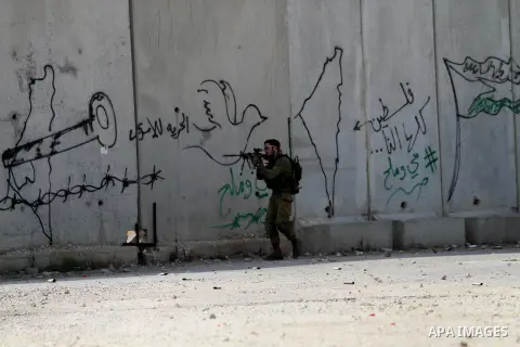 An Israeli soldier aims at Palestinian protesters during clashes in the West Bank town of Tulkarm, October 20, 2015. Triggered by Israeli incursions into the Al-Aqsa Mosque compound last month, violence and protests agai...