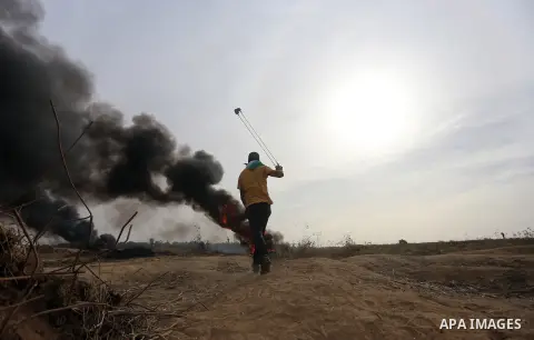 A Palestinian protester uses a sling shot to throw stones during clashes with Israeli security forces near the border between Israeli and central Gaza Strip, on October 23, 2015. Palestinian factions called for mass rall...