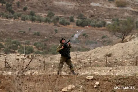 A member of Israeli security forces fires tear gas at Palestinian protesters during clashes at the Hawara checkpoint, south of the West Bank city of Nablus on October 22, 2015. Palestinian factions called for mass rallie...