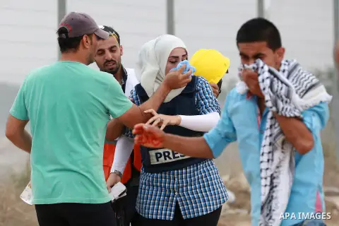 Palestinian journalists run for cover as they suffer from tear gas fired by Israeli security forces during clashes with Palestinian protesters near the border between Israeli and central Gaza Strip, on October 23, 2015....