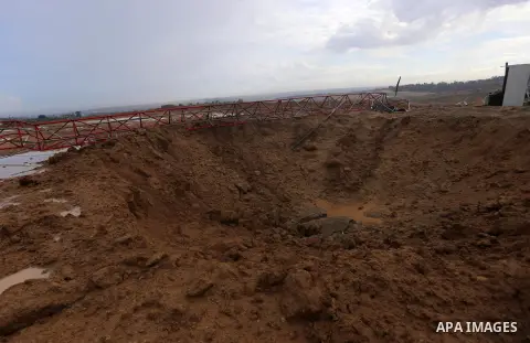 Palestinians walk near a huge crater following an Israeli air strike on a Hamas police facility near the border fence between Israel and the central Gaza Strip on October 27, 2015. Israel carried out an air strike agains...