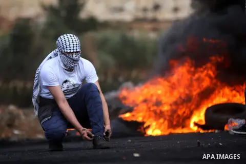 A masked Palestinian protester looks on during clashes with Israeli security forces near the Jewish settlement of Beit El, near the West Bank city of Ramallah October 27, 2015. The current round of violence began last mo...