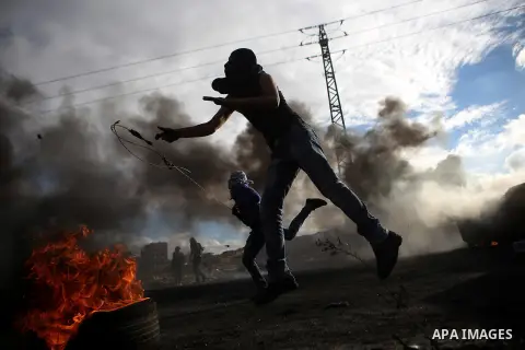 A Palestinian protester uses a sling shot to hurl stones at Israeli troops during clashes near the Jewish settlement of Bet El, near the West Bank city of Ramallah, October 29, 2015. Israeli security forces shot dead two...