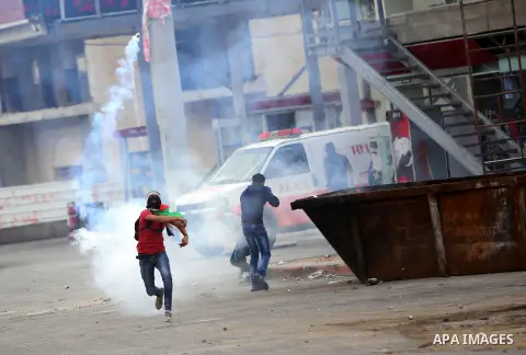 A Palestinian protester throws back a tear gas canister fired by Israeli troops during clashes near the Jewish settlement of Bet El, near the West Bank city of Ramallah, October 30, 2015. Since the start of October, viol...