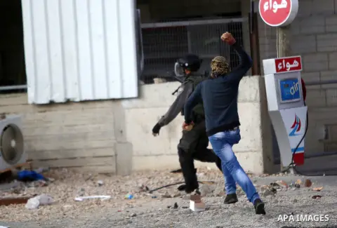 A Palestinian protester runs after an Israeli soldier during clashes near the Jewish settlement of Bet El, near the West Bank city of Ramallah, October 30, 2015. Since the start of October, violence that has included sta...