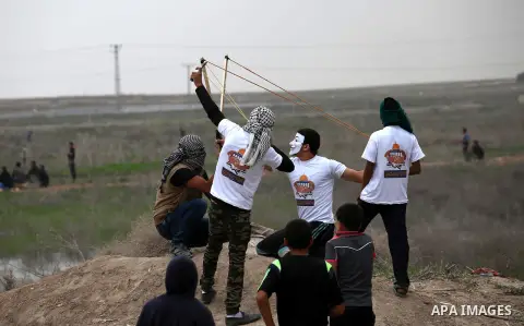 Palestinian protesters use a big sling shot to throw stones towards Israeli security forces during clashes near the border between Israel and eastern Gaza city, November 6, 2015. The current wave of violence erupted in m...