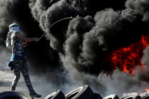 A Palestinian protester uses a sling shot to throw stones towards Israeli security forces during clashes in Beit El on the outskirts of the West Bank city of Ramallah, November 13, 2015. According to reports, 22 Palestin...
