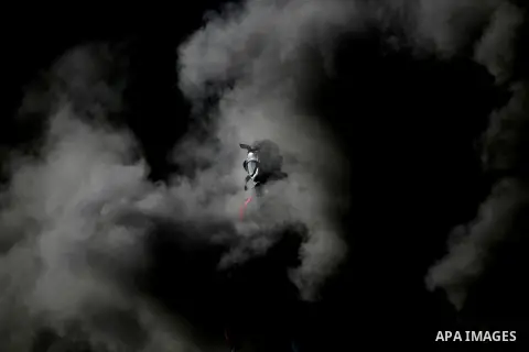 A masked Palestinian protester throws stones behind a smoke cloud during clashes with Israeli security forces in Beit El on the outskirts of the West Bank city of Ramallah, November 13, 2015. According to reports, 22 Pal...