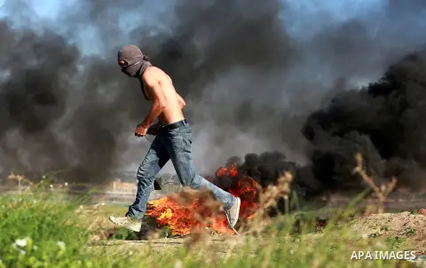 A Palestinian protester run for cover during clashes with Israeli troops near the border between Israel and central Gaza strip, November 13, 2015. The current wave of violence erupted in mid-September, fueled by rumors t...
