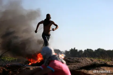 A Palestinian protester run for cover during clashes with Israeli troops near the border between Israel and central Gaza strip, November 13, 2015. The current wave of violence erupted in mid-September, fueled by rumors t...