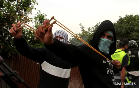 Palestinian protesters use slingshots to throw stones at Israeli security forces during clashes in the West Bank town of Qalqilya, on November 15, 2015. Palestinians commemorate the 27th anniversary of the declaration of...
