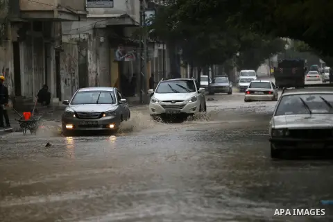 Palestinians walk in a flooded street during a rainy day in Gaza city on November 17, 2015. Photo by Yasser Qudih
