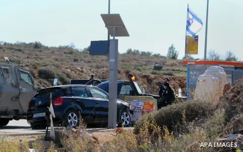 Israeli border guards stand in front of a damaged car at the spot where a Palestinian man was shot by Israeli forces after reportedly ramming a vehicle into a number of Israeli troops, wounding two soldiers and one borde...