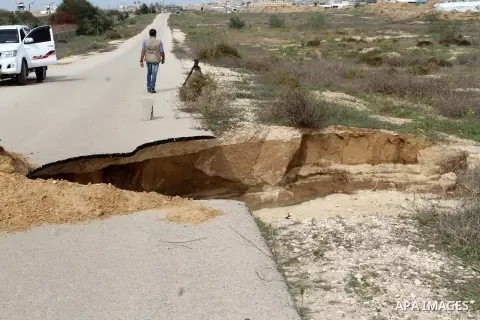 Palestinians stand next to a landslide made by the seawater pumped into the area by the Egyptian army, near the border between Egypt and the southern Gaza Strip, November 25, 2015. Huge water pipes have been installed al...