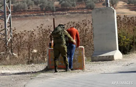 An Israeli soldier searches a Palestinian man before allowing him to pass through the Israeli Beit Forik military checkpoint near the West Bank city of Nablus November 29, 2015. Photo by Nedal Eshtayah