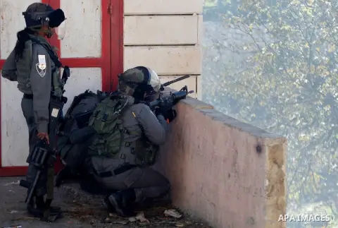 An Israeli soldier aims at Palestinian protesters during clashes in the village of Beit Ummar, near the city of Hebron in the Israeli occupied West Bank on Dec. 04, 2015. Photo by Wisam Hashlamoun