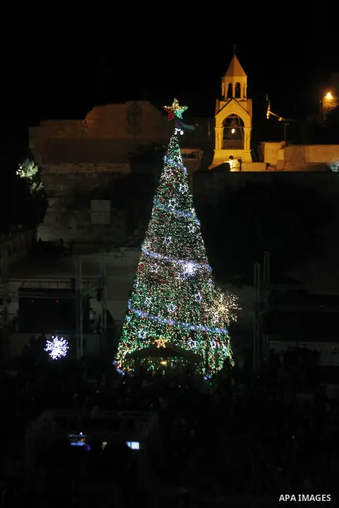 A general view showing people attending the lighting of the Christmas tree on Manger Square, in the West Bank city of Bethlehem, 05 December 2015, as part of the preparations for Christmas. In the background is the Churc...