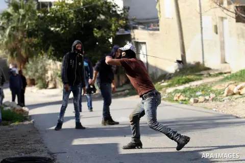A Palestinian protester uses a slingshot to hurl stones towards Israeli security forces during clashes following a demonstration against the expropriation of Palestinian land by Israel in the village of Kfar Qaddum, near...