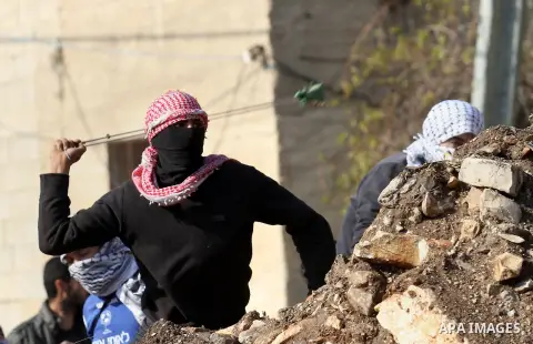 A Palestinian protester uses a slingshot to hurl stones towards Israeli security forces during clashes following a demonstration against the expropriation of Palestinian land by Israel in the village of Kfar Qaddum, near...
