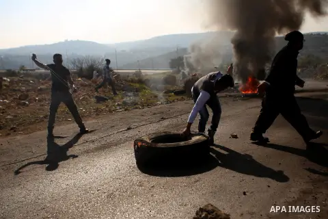 A Palestinian protester burns tires during clashes between Palestinian youth and Israeli army on December 11, 2015 in the occupied West Bank village of Silwad, northeast of Ramallah after a demonstration to call for the...