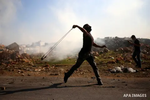 A Palestinian protester uses a slingshot to throw stones during clashes between Palestinian youth and Israeli army on December 11, 2015 in the occupied West Bank village of Silwad, northeast of Ramallah after a demonstra...