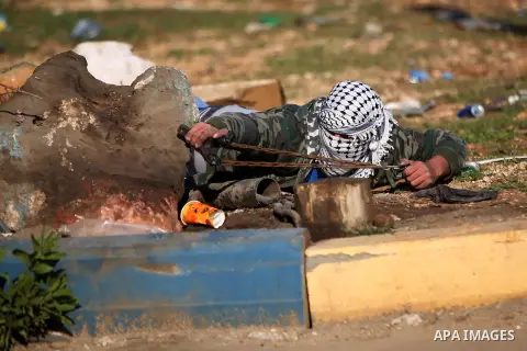 A Palestinian protester uses a slingshot to throw stones during clashes between Palestinian youth and Israeli army on December 11, 2015 in the occupied West Bank village of Silwad, northeast of Ramallah after a demonstra...