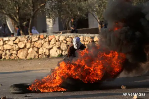 A Palestinian protester burns tires during clashes between Palestinian youth and Israeli army on December 11, 2015 in the occupied West Bank village of Silwad, northeast of Ramallah after a demonstration to call for the...