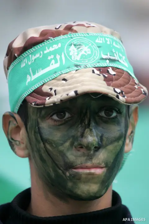 Palestinians attend a military parade by members of the Ezzedine al-Qassam Brigades, the armed wing of the Hamas movement, on December 11, 2015, to mark the ruling Islamist movement's 28th birthday in Khan Yunis, in the...
