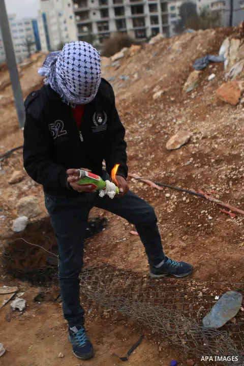A Palestinian protester throw a molotov cocktail towards Israeli security forces during clashes in Beit El on the outskirts of the West Bank city of Ramallah, Dec.12, 2015. Photo by Shadi Hatem